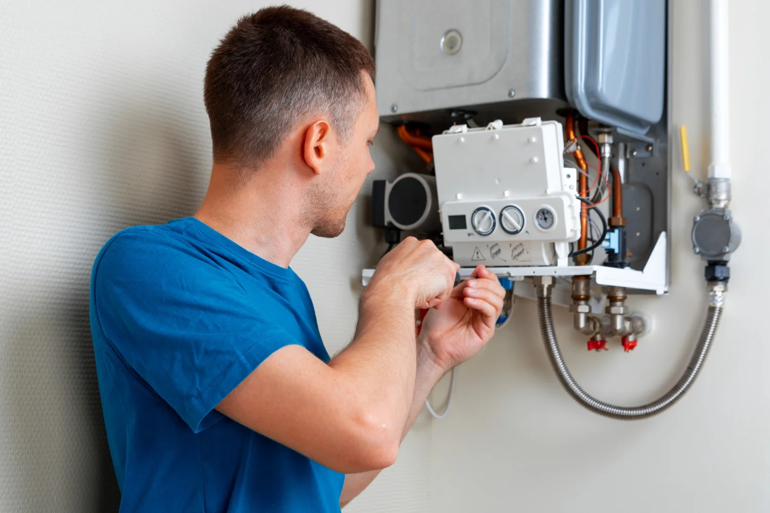 Man repairing wall-mounted gas boiler at home
