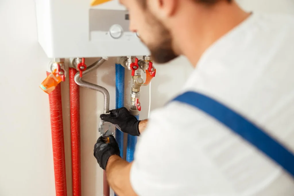Plumber repairing boiler pipes with spanner