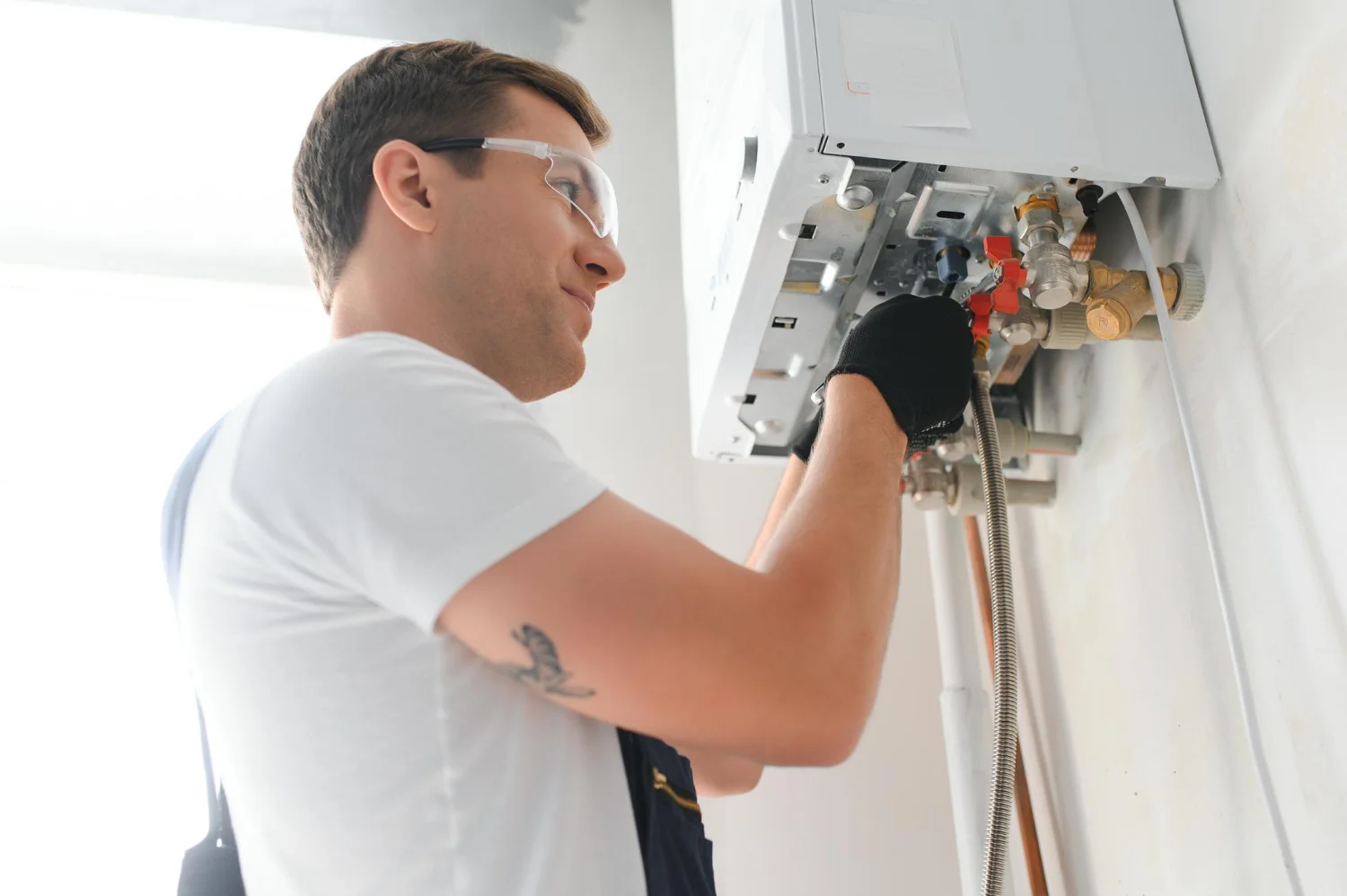 Plumber repairing wall-mounted boiler indoors