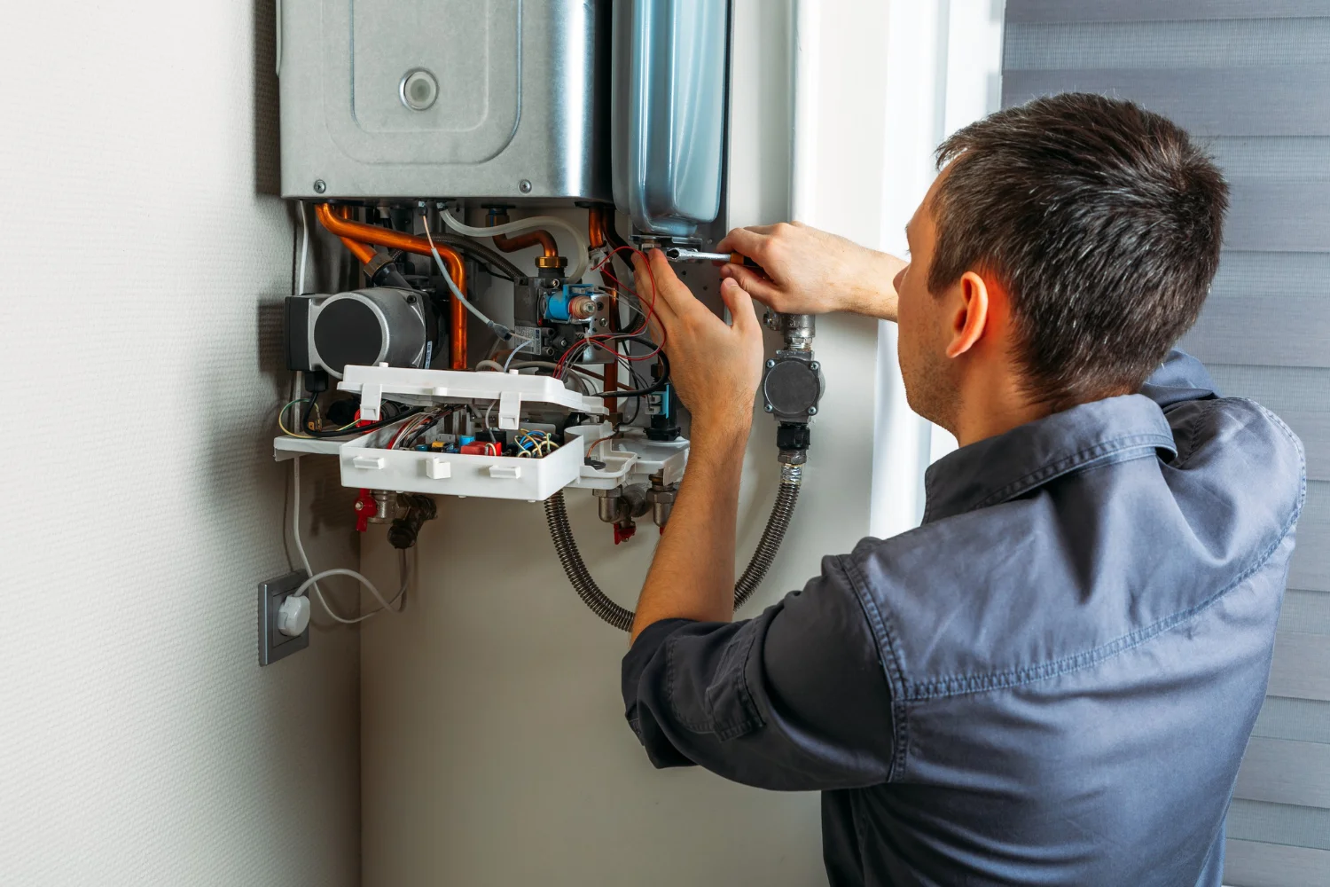 Engineer repairing wall-mounted gas boiler at home