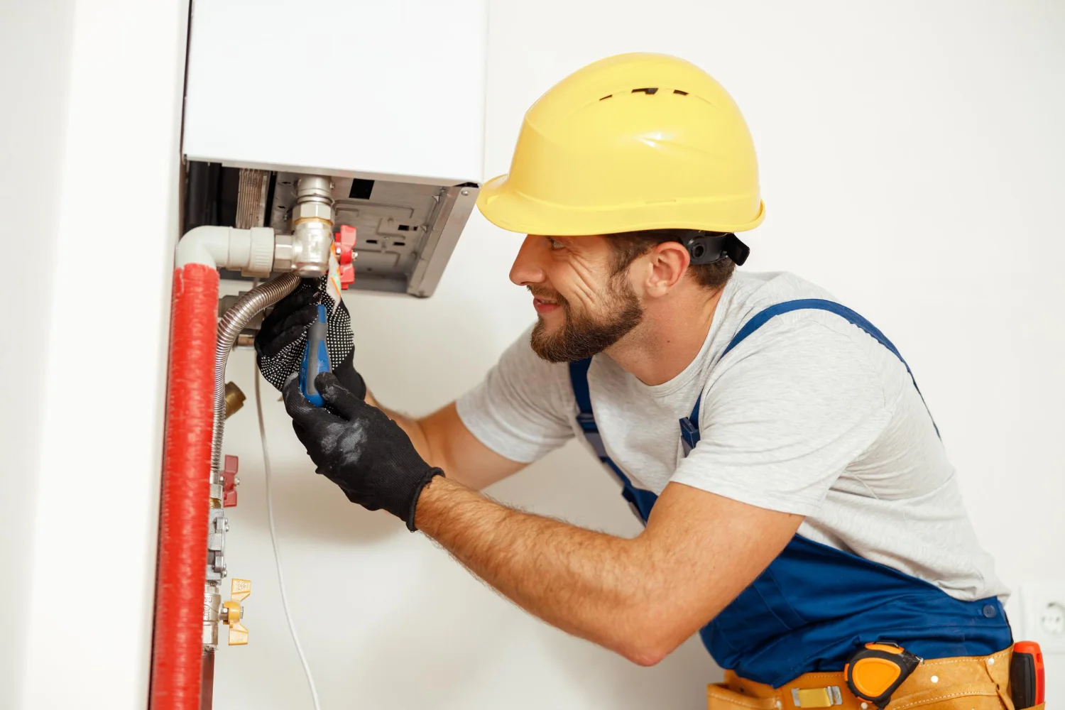 Plumber repairing boiler pipes with spanner