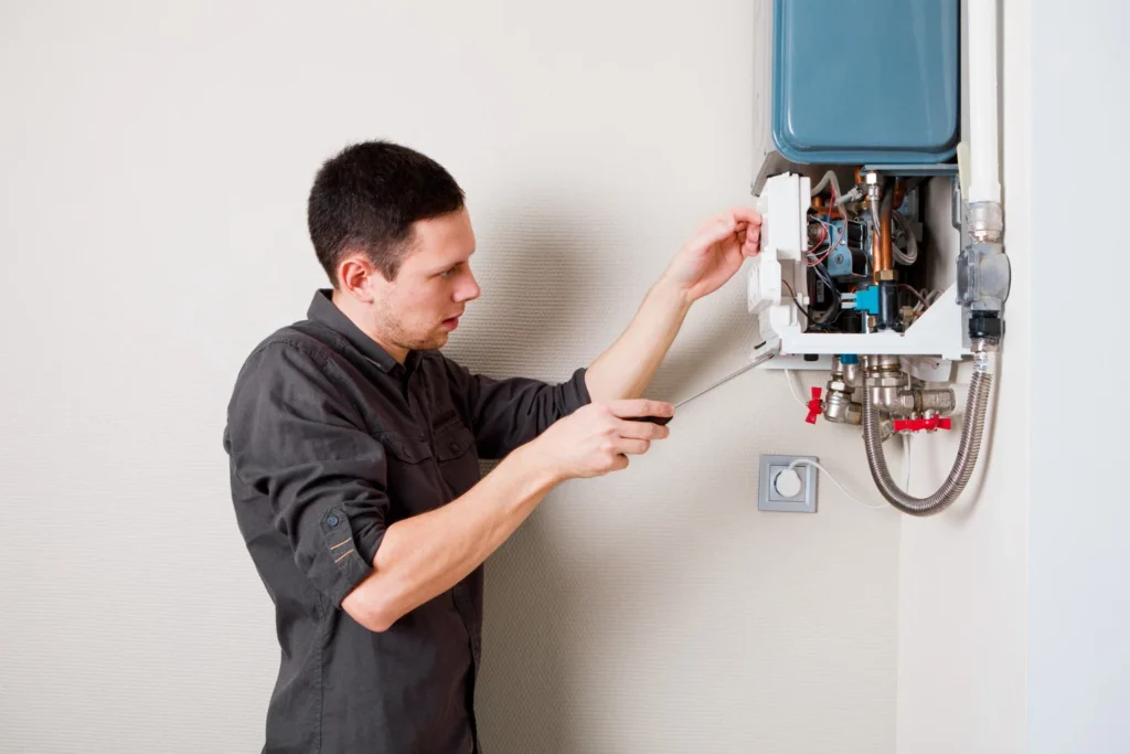 Technician repairing wall-mounted boiler with screwdriver