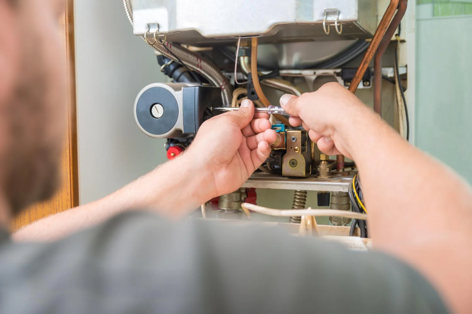 Engineer repairing domestic boiler with screwdriver