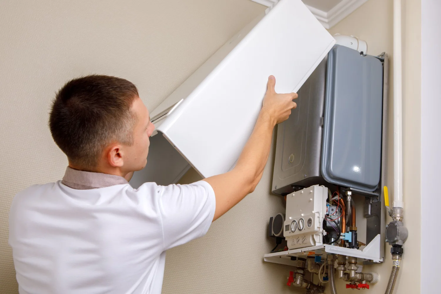 Engineer removing cover from wall-mounted boiler