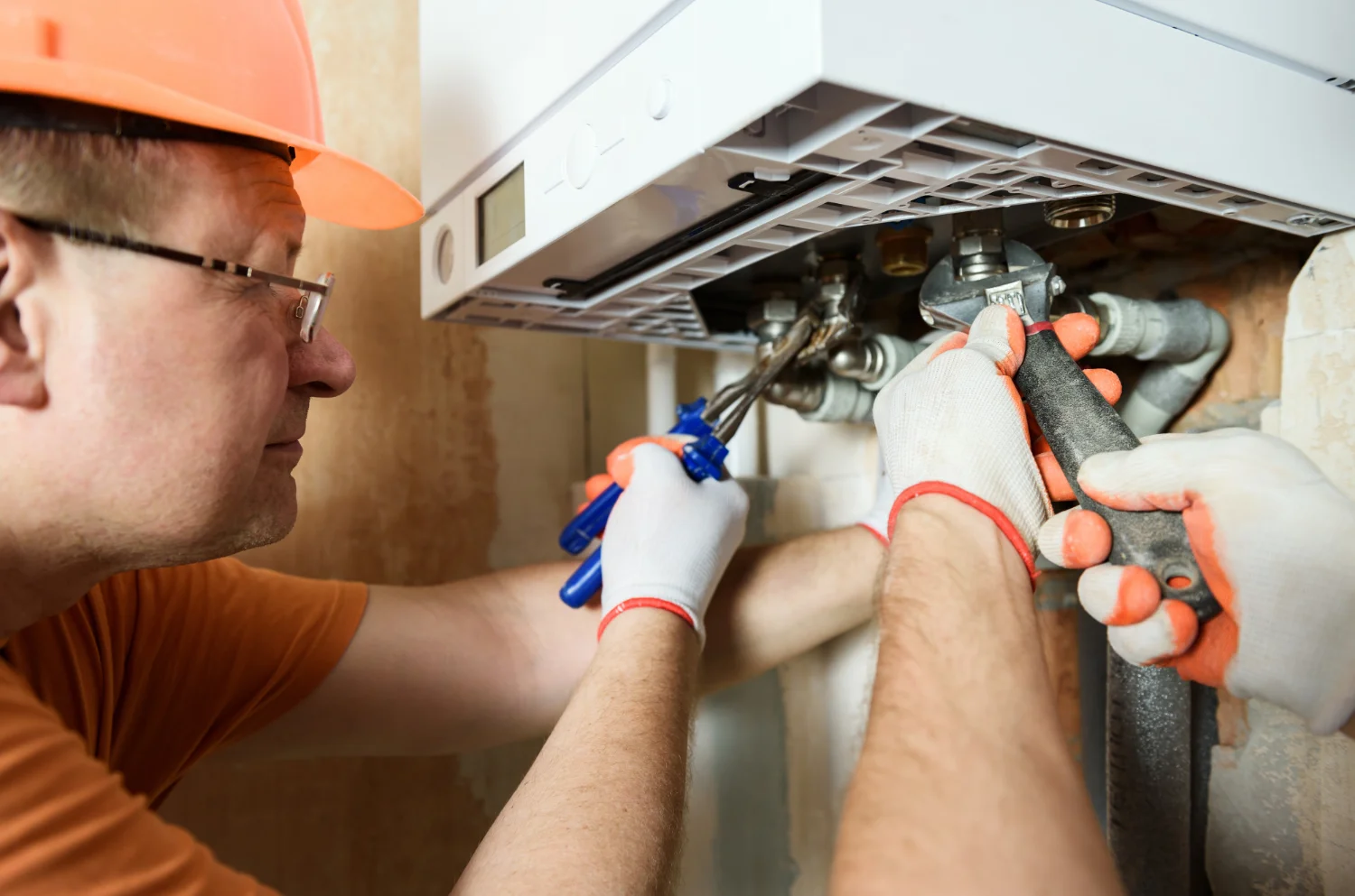 Engineer repairing boiler with wrench and screwdriver