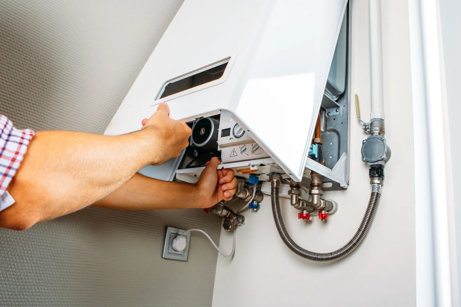 Technician servicing wall-mounted gas boiler unit